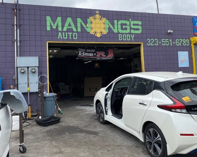 The shop's purple street wall, the name painted across it in green with a yellow sun for the letter O, the phone number painted to the right, and a white car parked at the open bay.