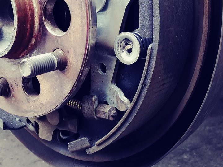 A close-up of a brake drum with the shoes and springs exposed at the wheel.